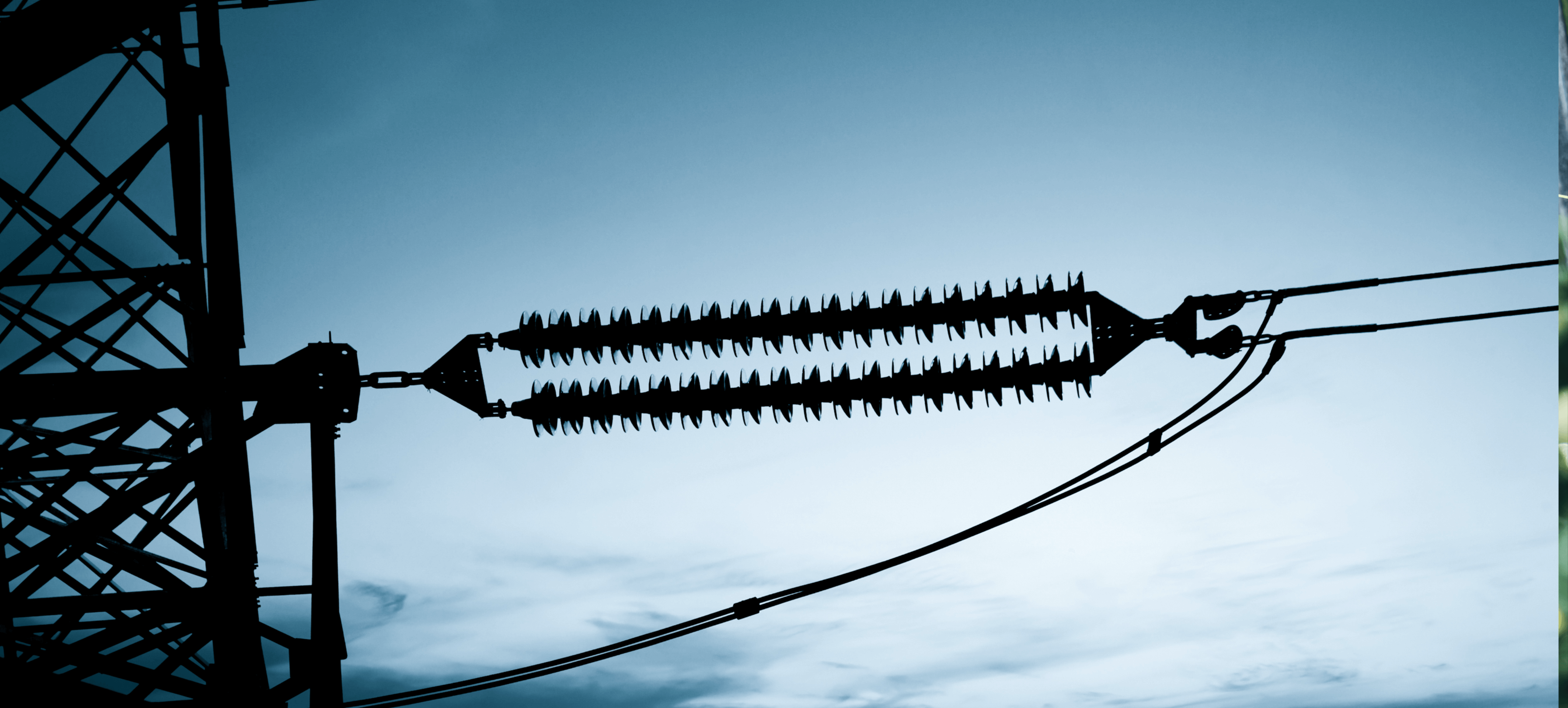 Elektromaterial: Isolatoren und Hochspannungsleitungen vor einem blauen Himmel.